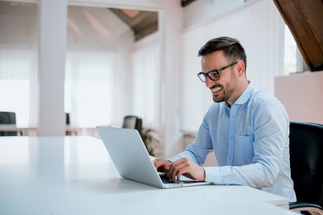 Junger Mann im Business-Hemd am Laptop sitzend: Die Digitalisierung hat es möglich gemacht, dass Verbraucherinnen und Verbraucher heute einen Kredit online unterschreiben und komplett papierlos aufnehmen können - mit Hilfe der digitalen Unterschrift!